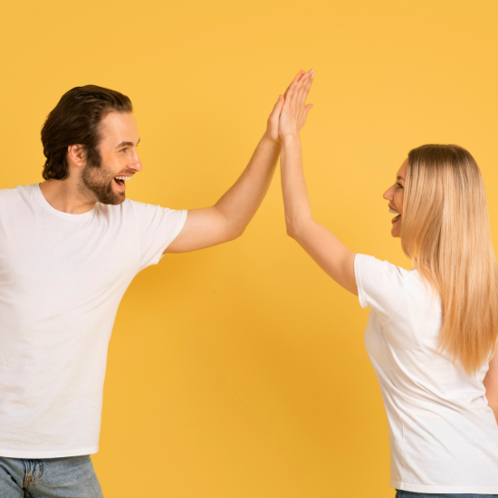 Deux personnes se donnant un high five, souriantes, devant un fond jaune.