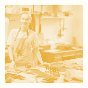 Femme souriante dans un atelier, entourée de matériel de travail.