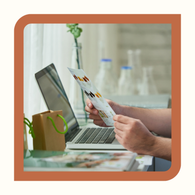 Une personne tient un document en consultant un ordinateur portable.